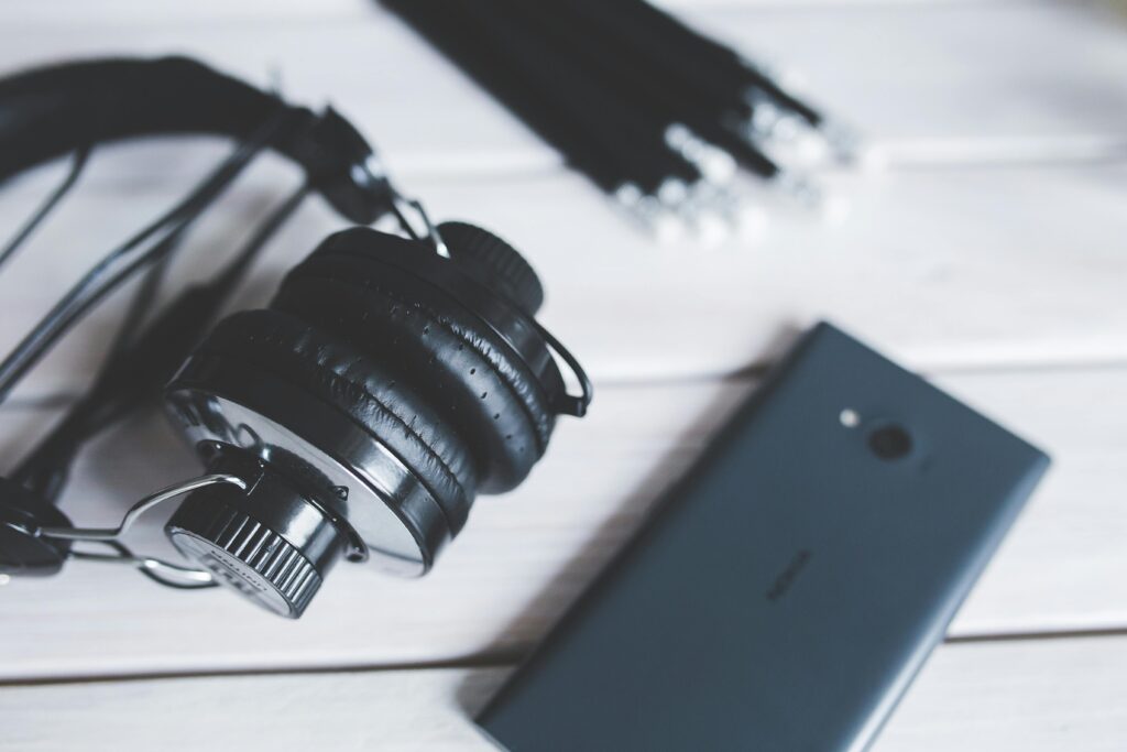 Close-up view of black headphones and smartphone on a wooden table, highlighting modern technology.